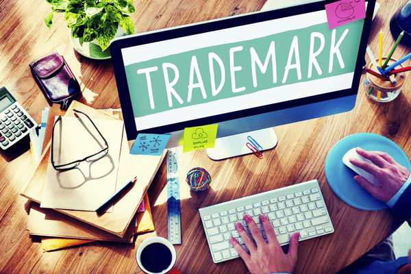 Hands working on a laptop with a trademark symbol overlay
